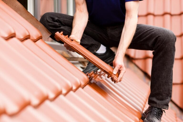 un ouvrier pose des tuiles en argile sur une toiture